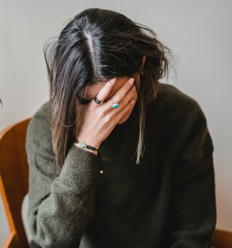 Woman head in hands contemplating trauma