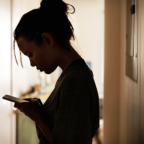 Adolescente masculino sentado en la pared mirando teléfono celular